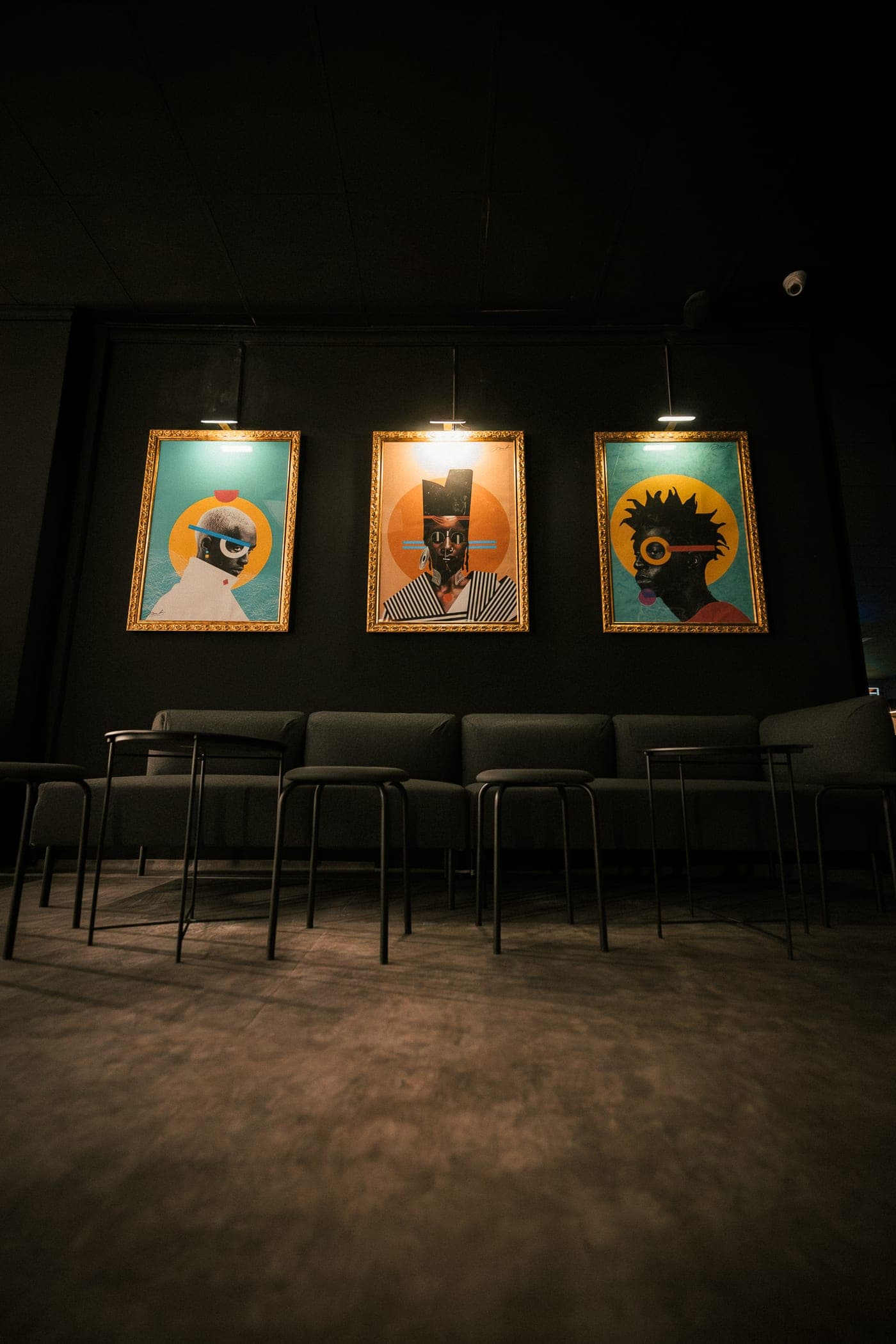 Tres retratos sobre el sofá gris, al fondo de la sala