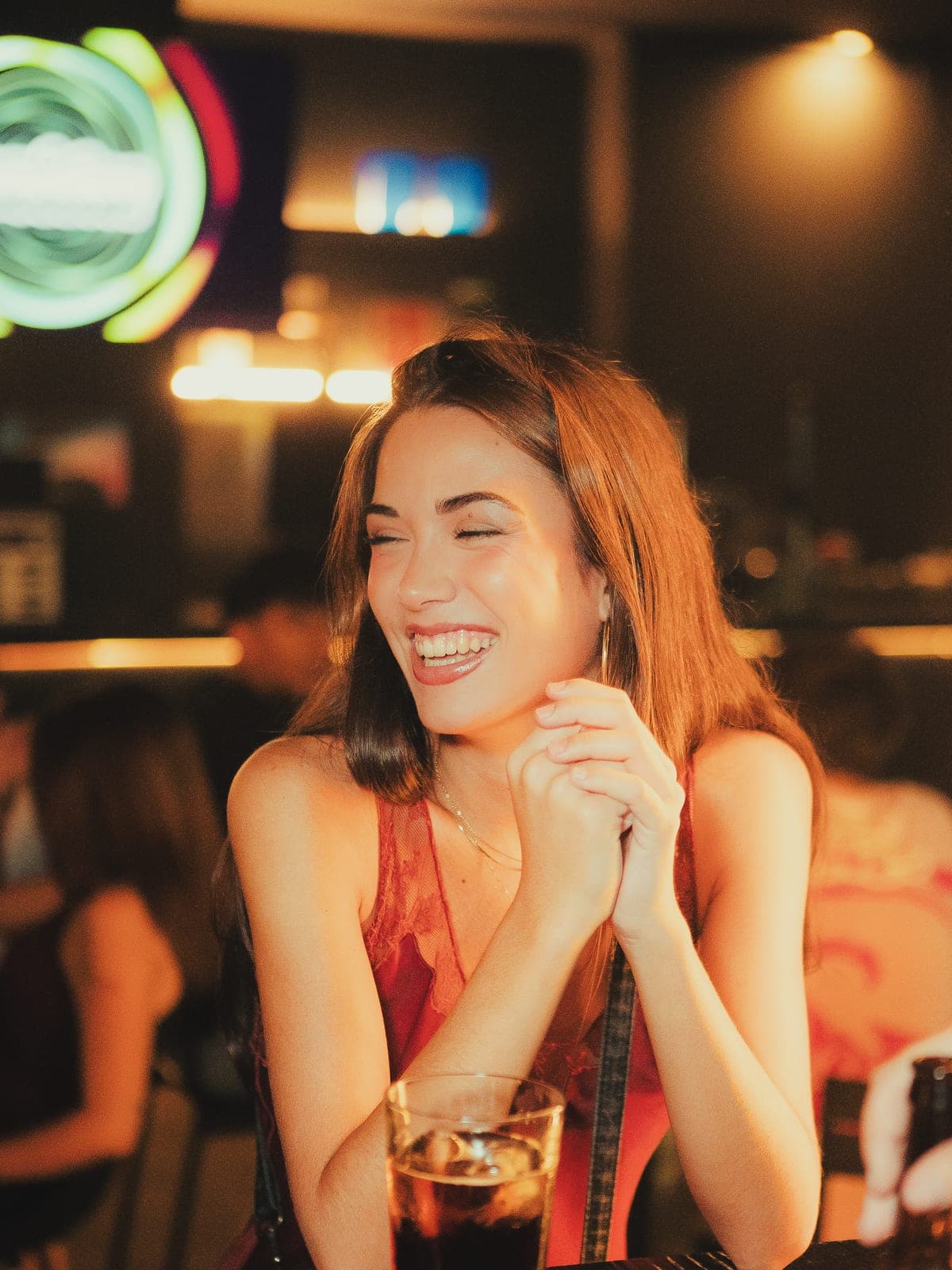 Una chica se ríe con la copa delante, con la sala al fondo