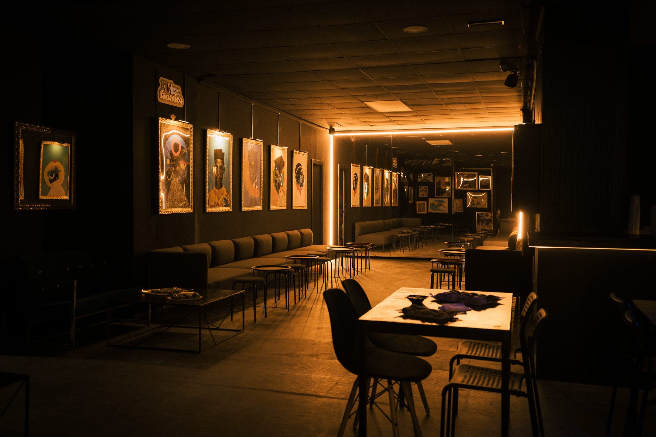 La sala de Fanático: banquetas, mesas y los cuadros pop-art en marcos dorados