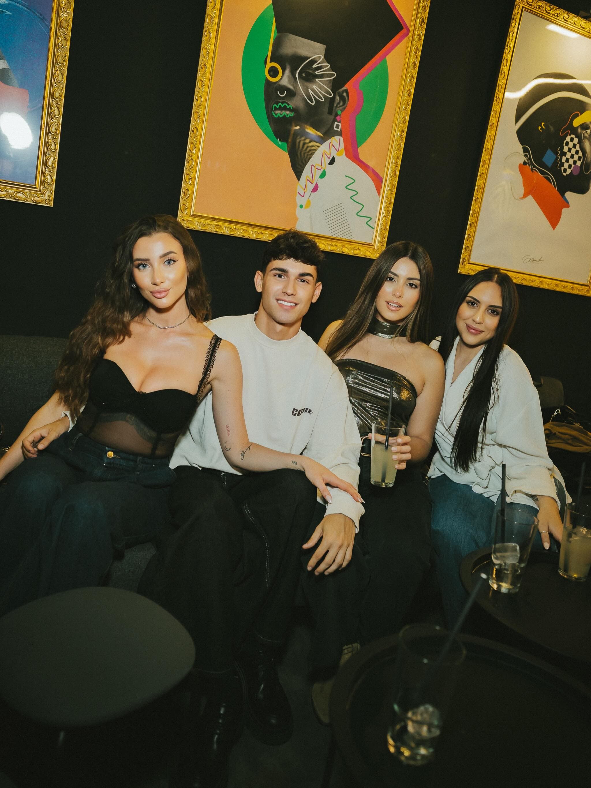 Grupo de amigos en los sofás de Fanático, bajo los cuadros pop-art