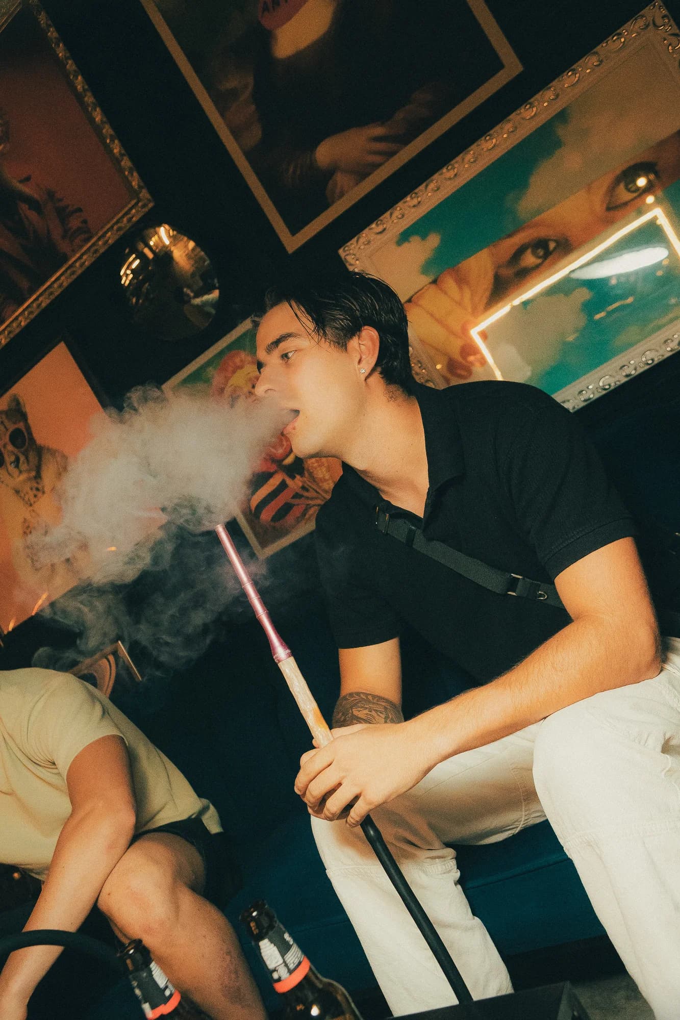 Una chica suelta el humo de la shisha con la boquilla en la mano